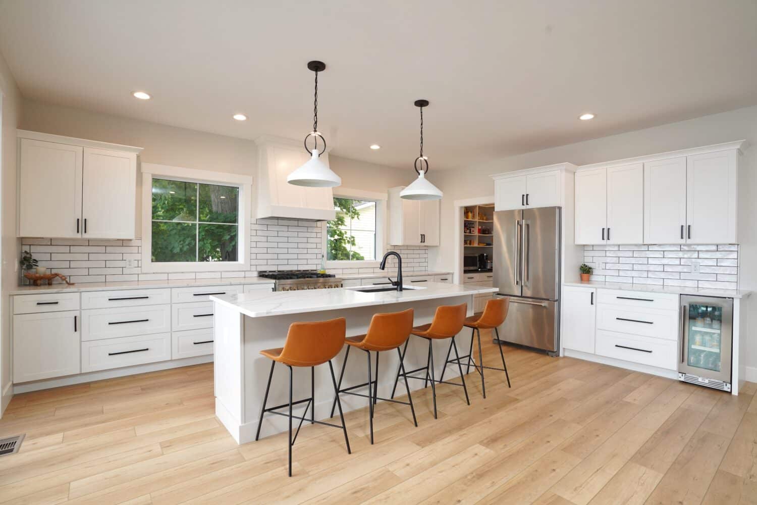 Contemporary kitchen with white cabinets, island, bar stools, and stainless steel appliances.