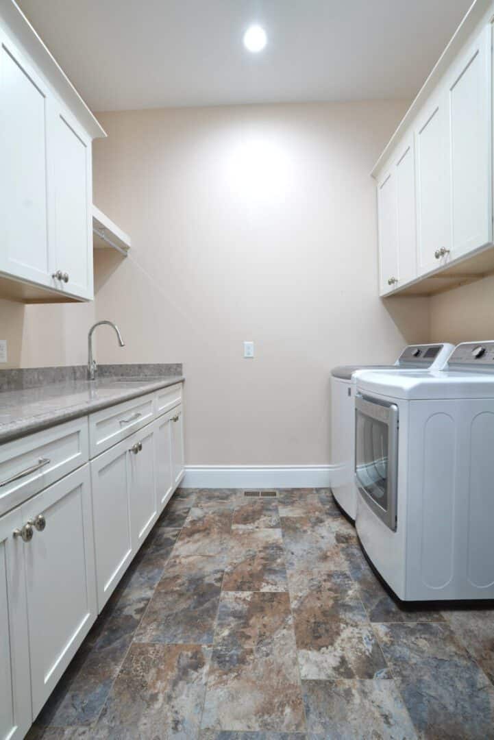 Clean laundry room with white cabinets, washer, and sink for home convenience.