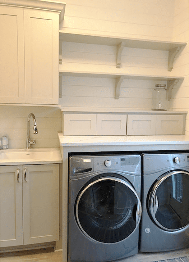 Contemporary laundry room with white cabinets and stainless steel washer and dryer.
