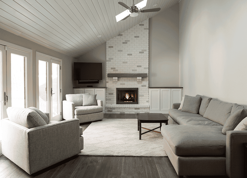Cozy living room with fireplace, gray sofas, and large windows.