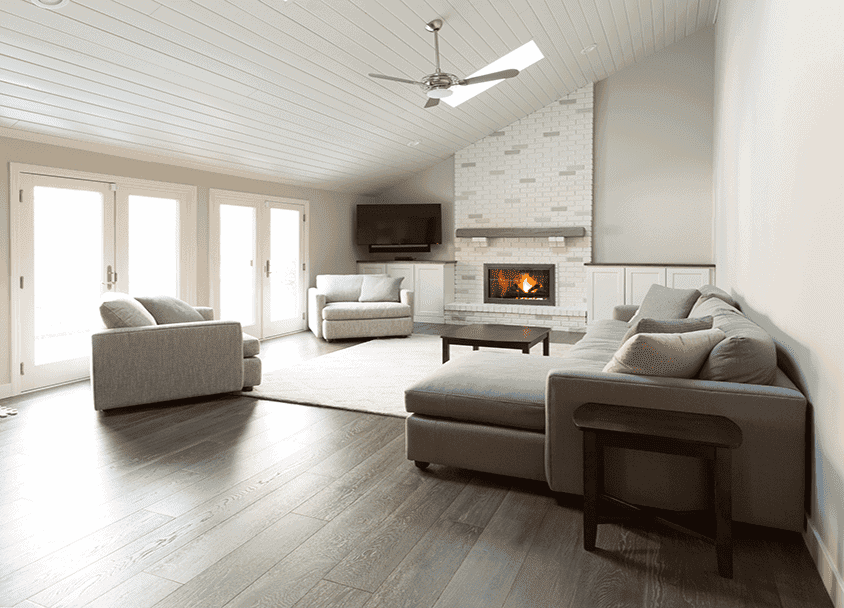 Spacious living room with white sofas, fireplace, and large windows.