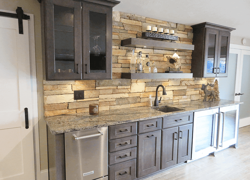 Contemporary kitchen with stone backsplash, dark cabinets, and stainless steel appliances.