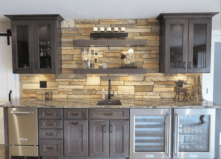 Contemporary kitchen with dark cabinetry and stone backsplash.