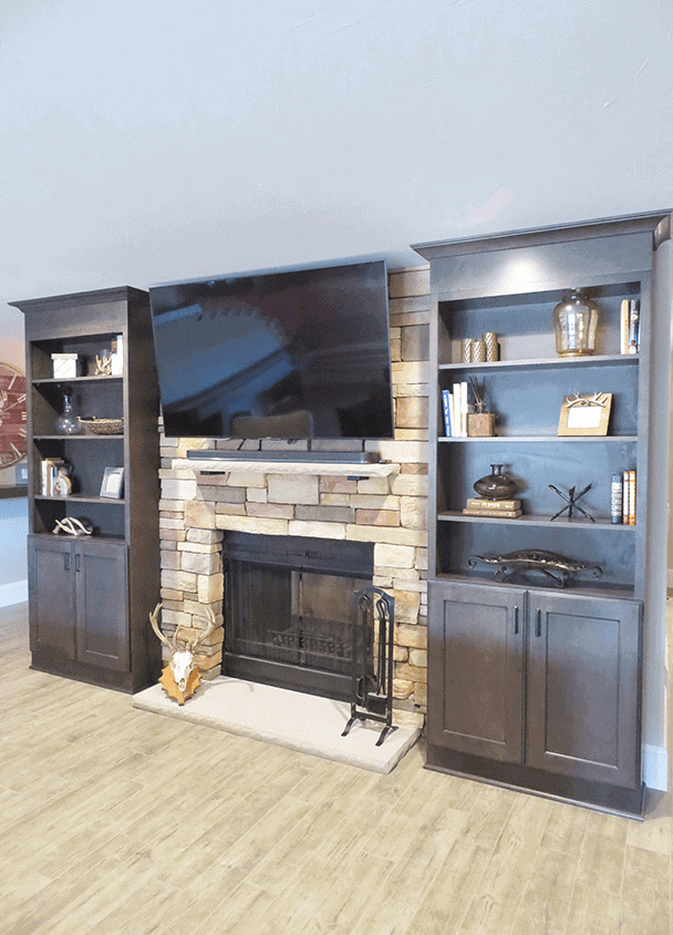 Contemporary living room with stone fireplace and dark wood shelving units on each side.