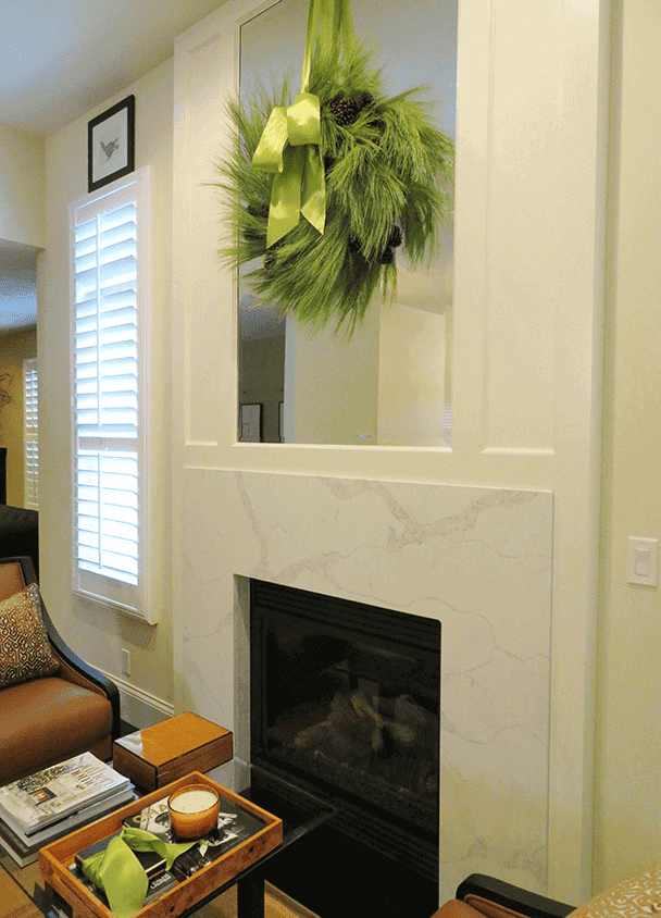 Contemporary fireplace with marble surround and festive green wreath.