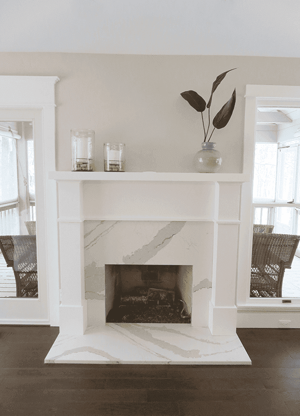 Modern white fireplace with marble surround and decorative vase on mantel.