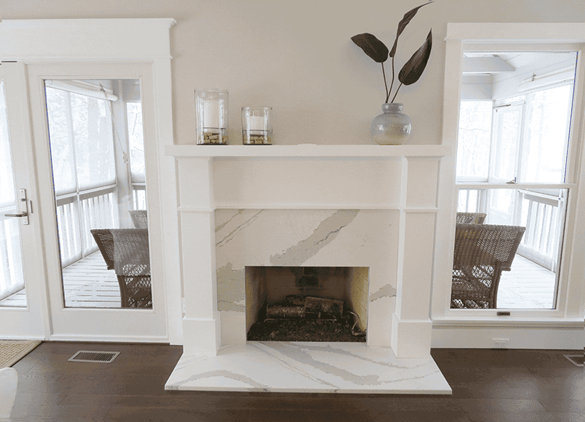 Contemporary living room with white marble fireplace and large windows.