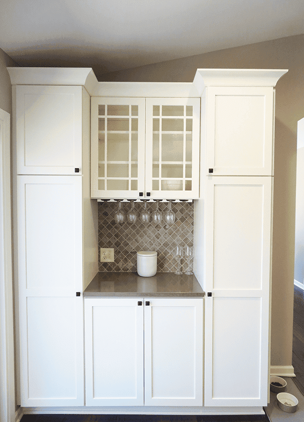 Elegant white kitchen cabinets with glass doors and wine glass storage.