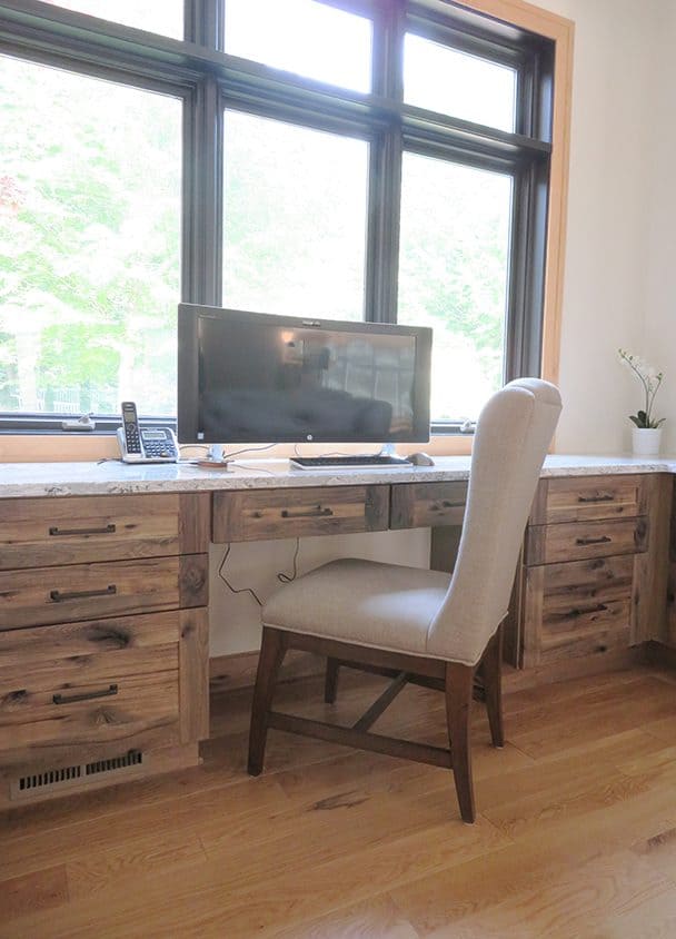 Home office with wooden desk, beige chair, and large window with natural light.