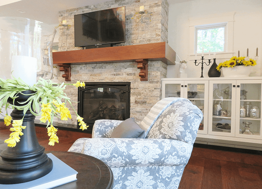 Cozy living room with stone fireplace, TV, and floral armchair.