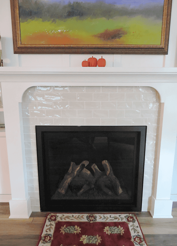 Contemporary fireplace with black insert and white tile surround in living room.