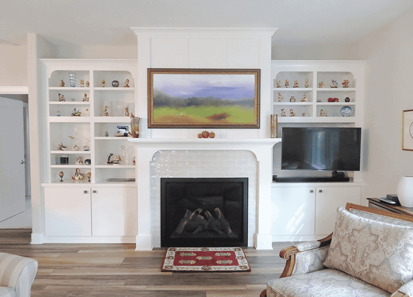 Living room with white built-in shelves, fireplace, and flat-screen TV.
