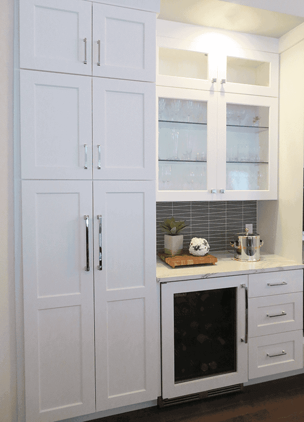 White kitchen cabinets with glass doors and built-in appliances.