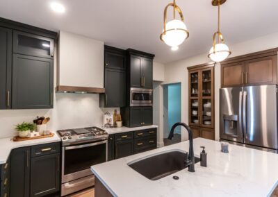 Contemporary kitchen with dark cabinets, stainless appliances, and white countertops.