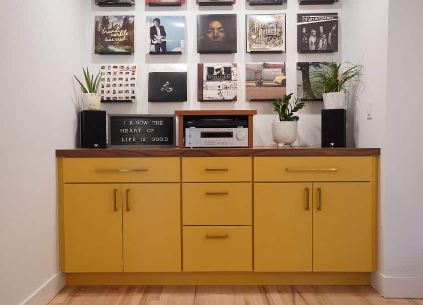 Yellow sideboard with plants and wall art in a contemporary interior.