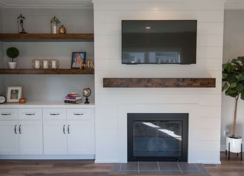 Contemporary living room with fireplace, wall-mounted TV, and decorative shelves.