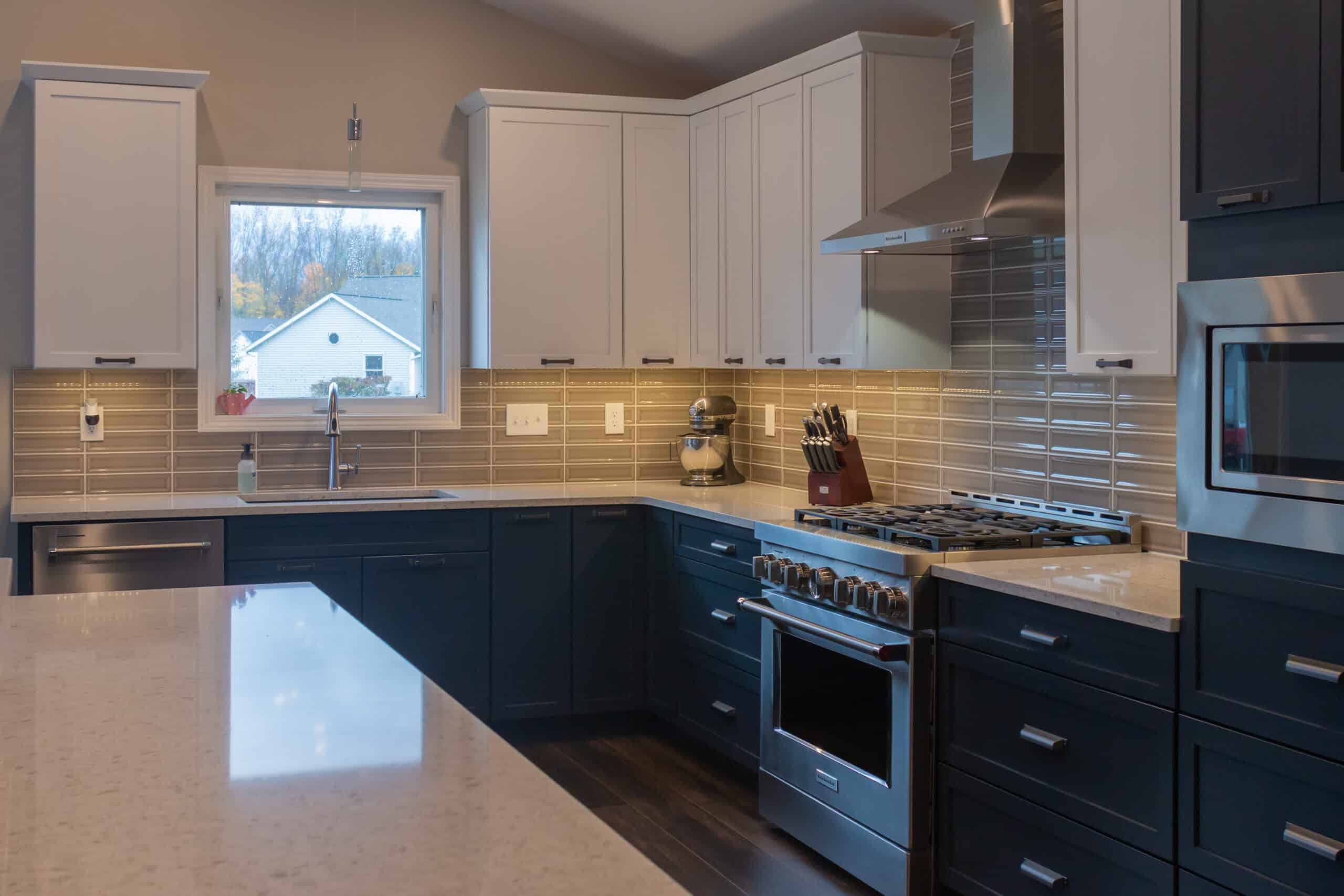 Contemporary kitchen with white upper and navy lower cabinets, stainless steel appliances, and a tan.