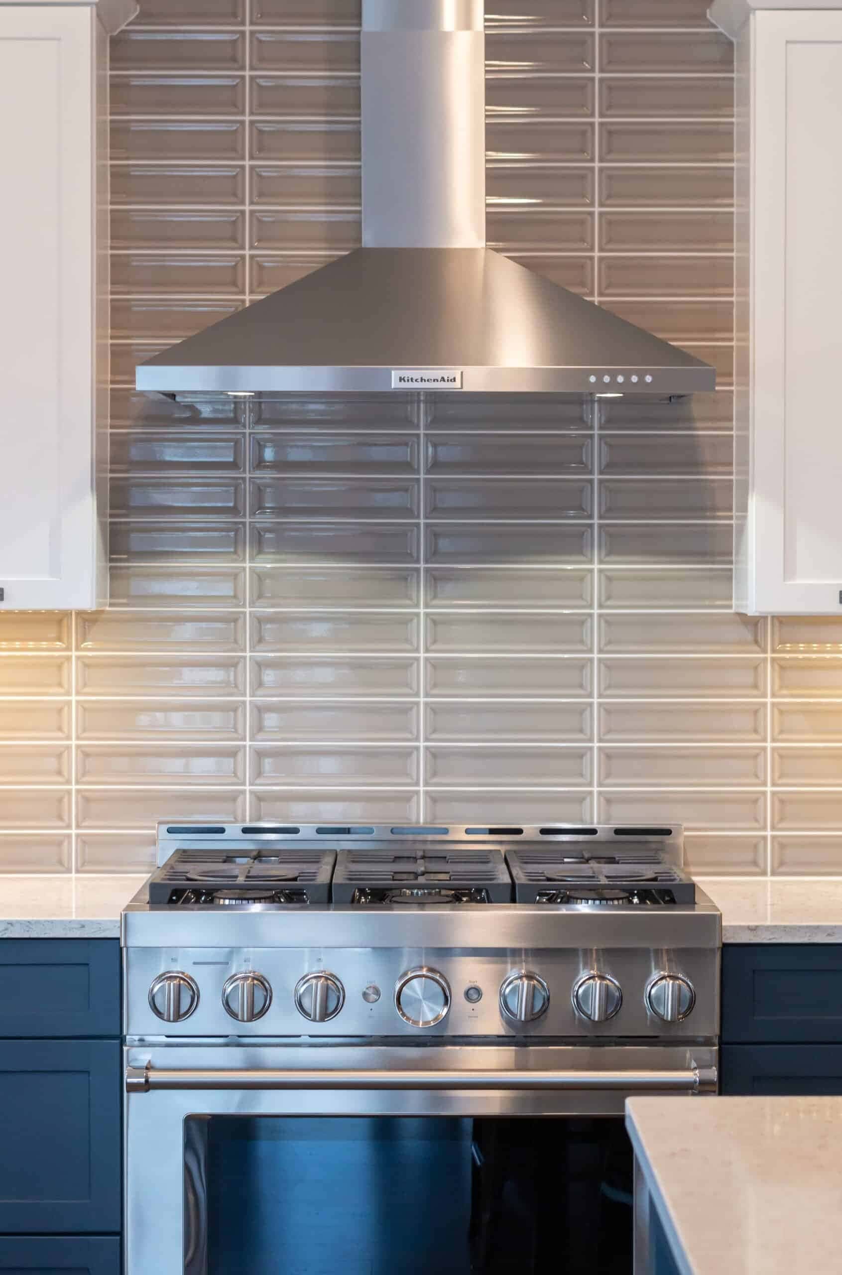 Stainless steel gas range with oven and hood in contemporary kitchen.