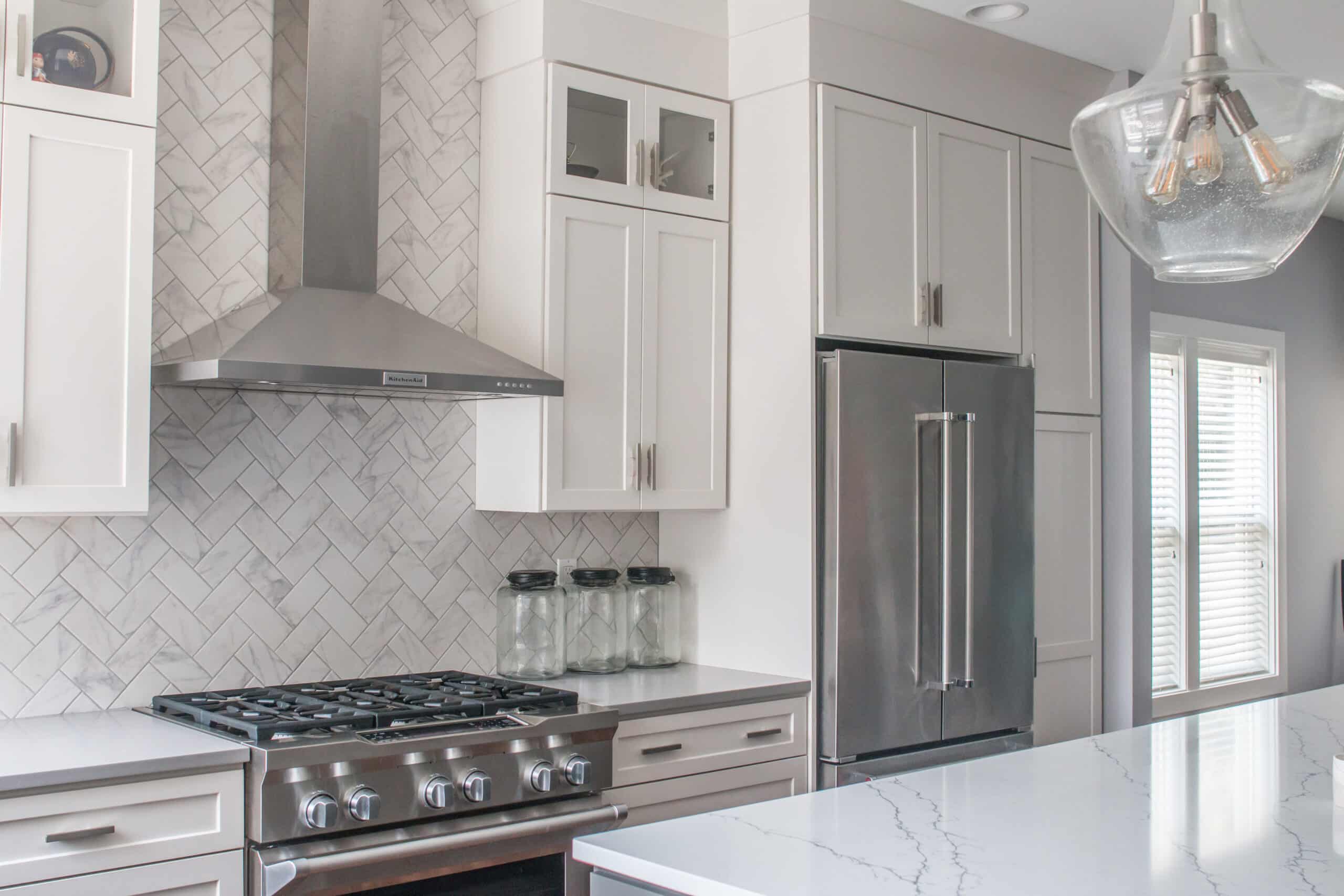Contemporary white kitchen with stainless steel appliances and marble countertops.