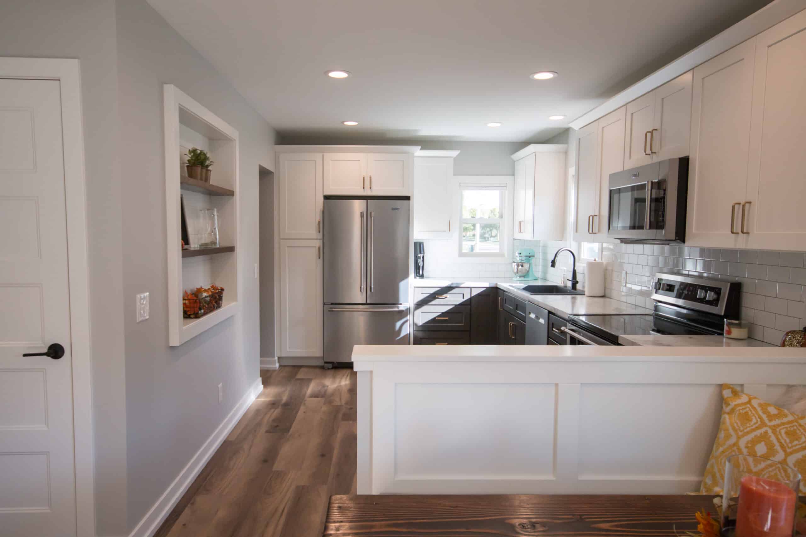 Contemporary kitchen with white cabinets, stainless steel appliances, and wooden flooring.