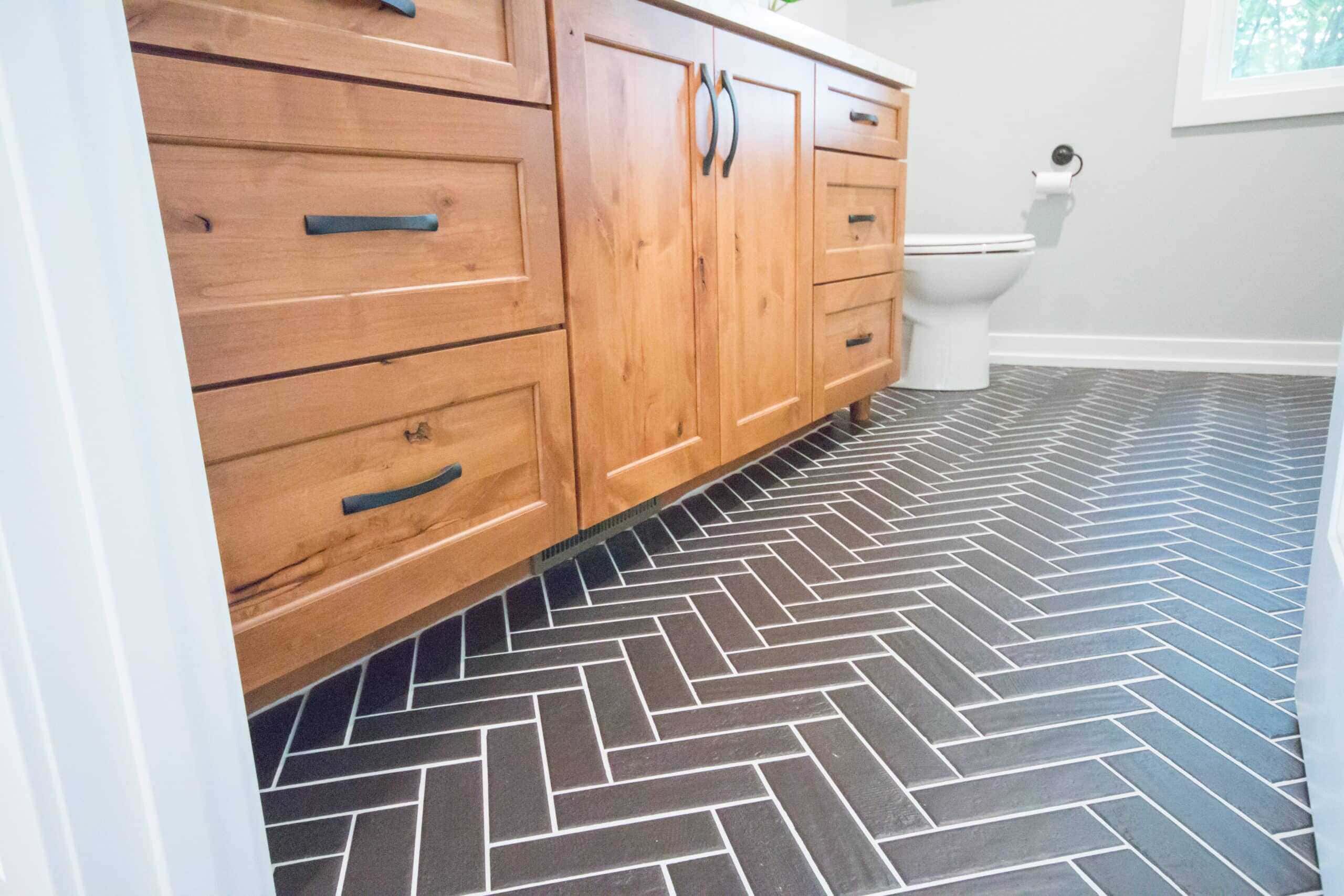 Bathroom with wooden cabinets and herringbone tile floor.