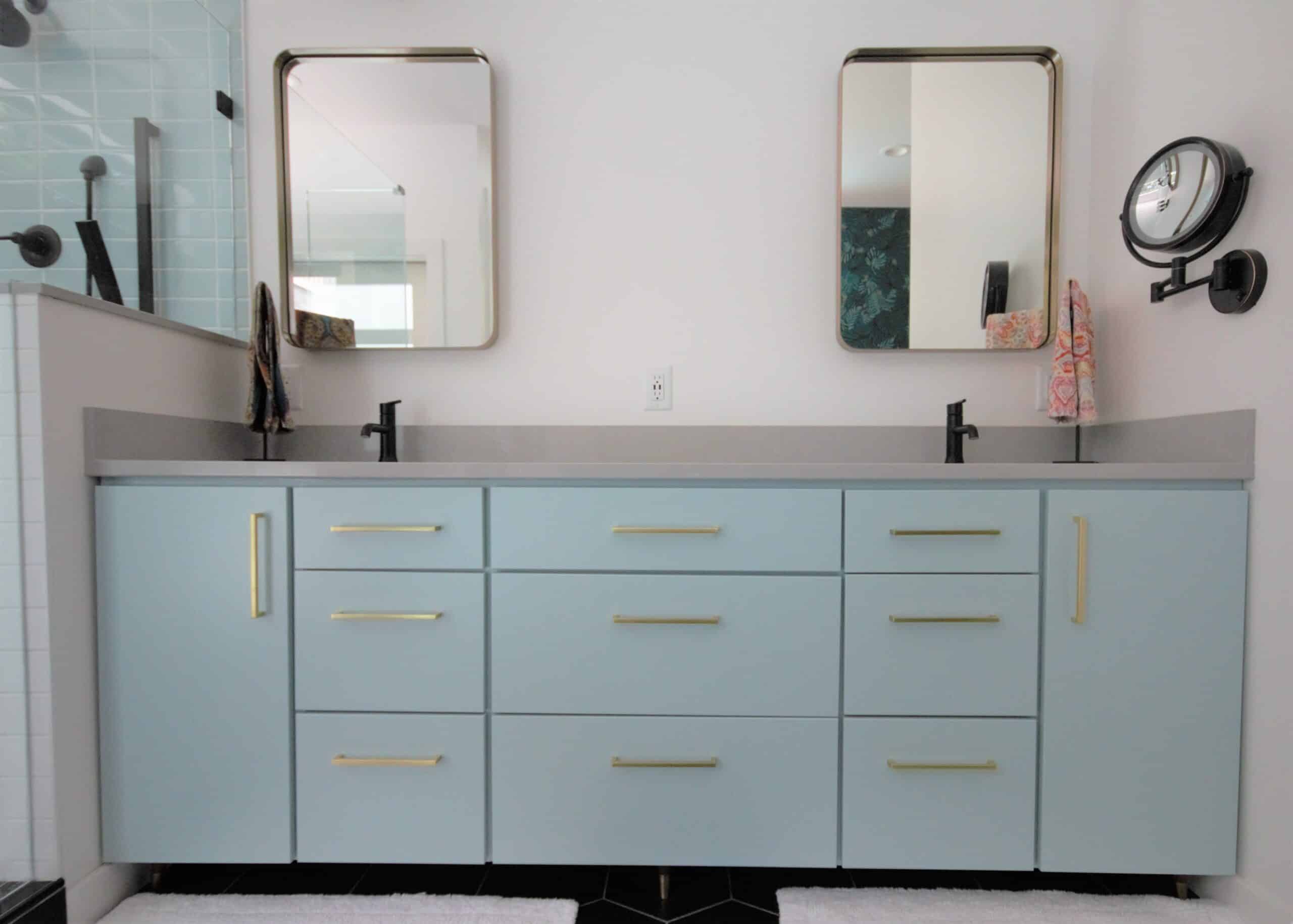 Light blue bathroom vanity with two mirrors and black fixtures.