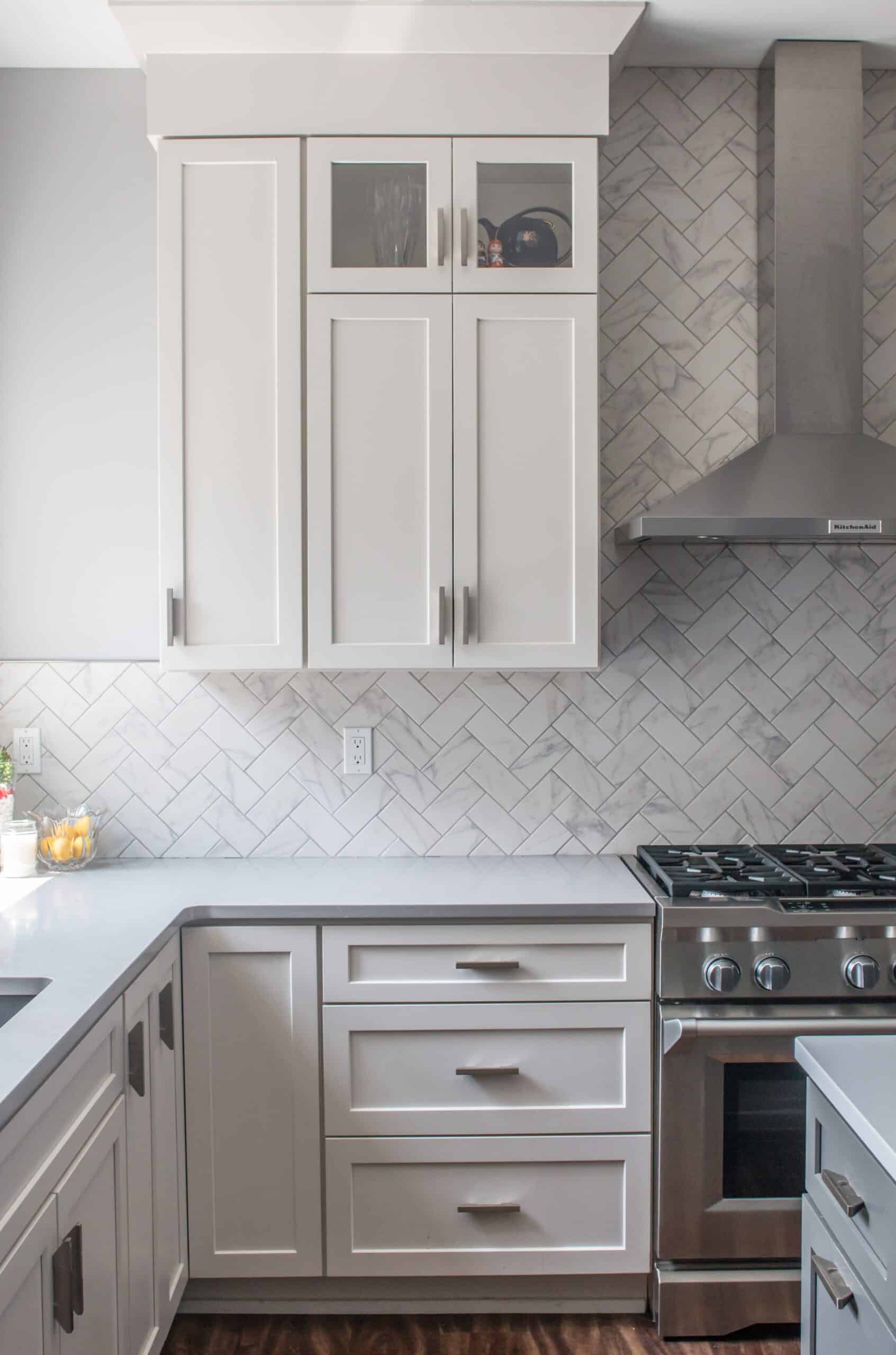 Contemporary white kitchen cabinets with glass doors and stainless steel stove.