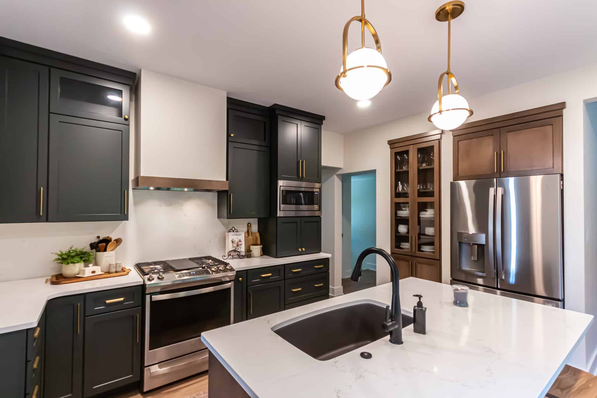 Contemporary kitchen with dark cabinetry, stainless steel appliances, and a white island.