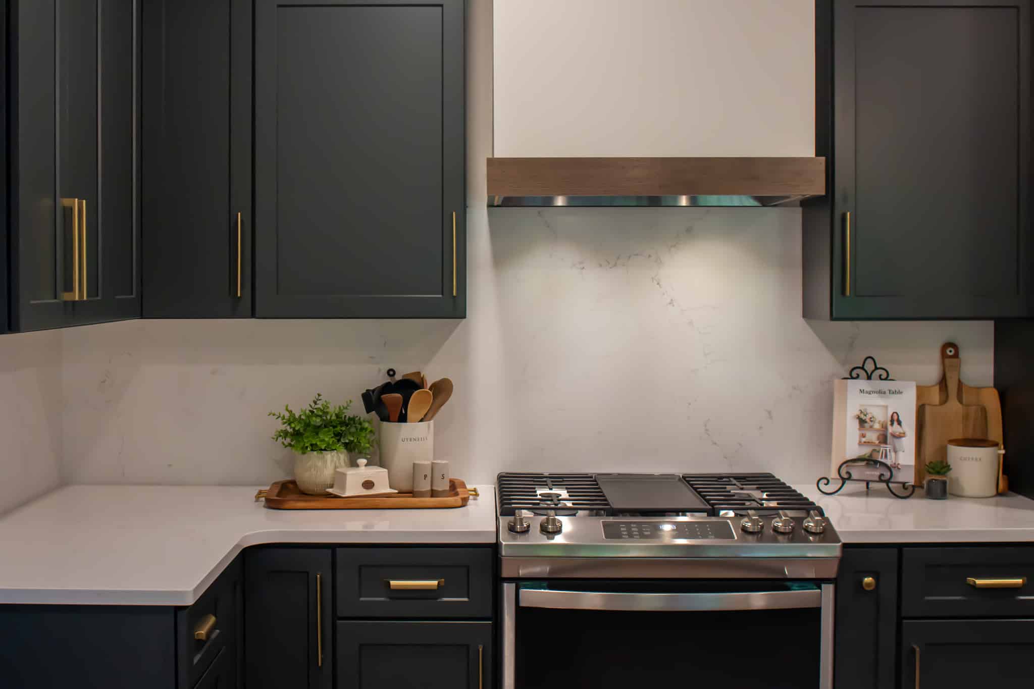 Contemporary kitchen with dark cabinets, white countertops, and stainless steel stove.