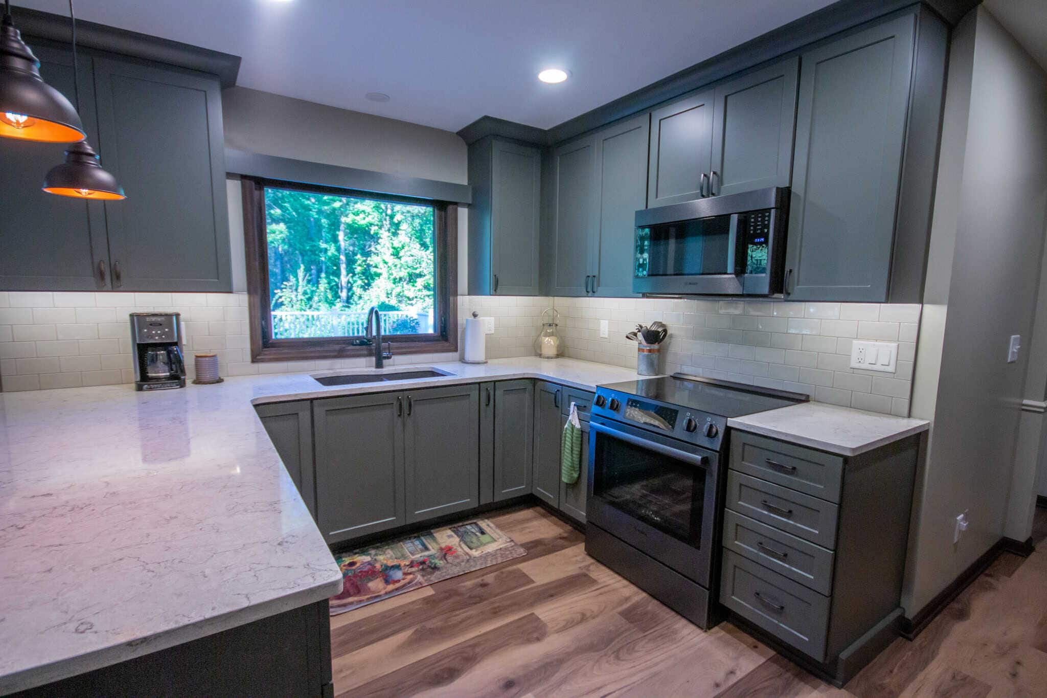 Contemporary gray kitchen with stainless steel appliances and large window.