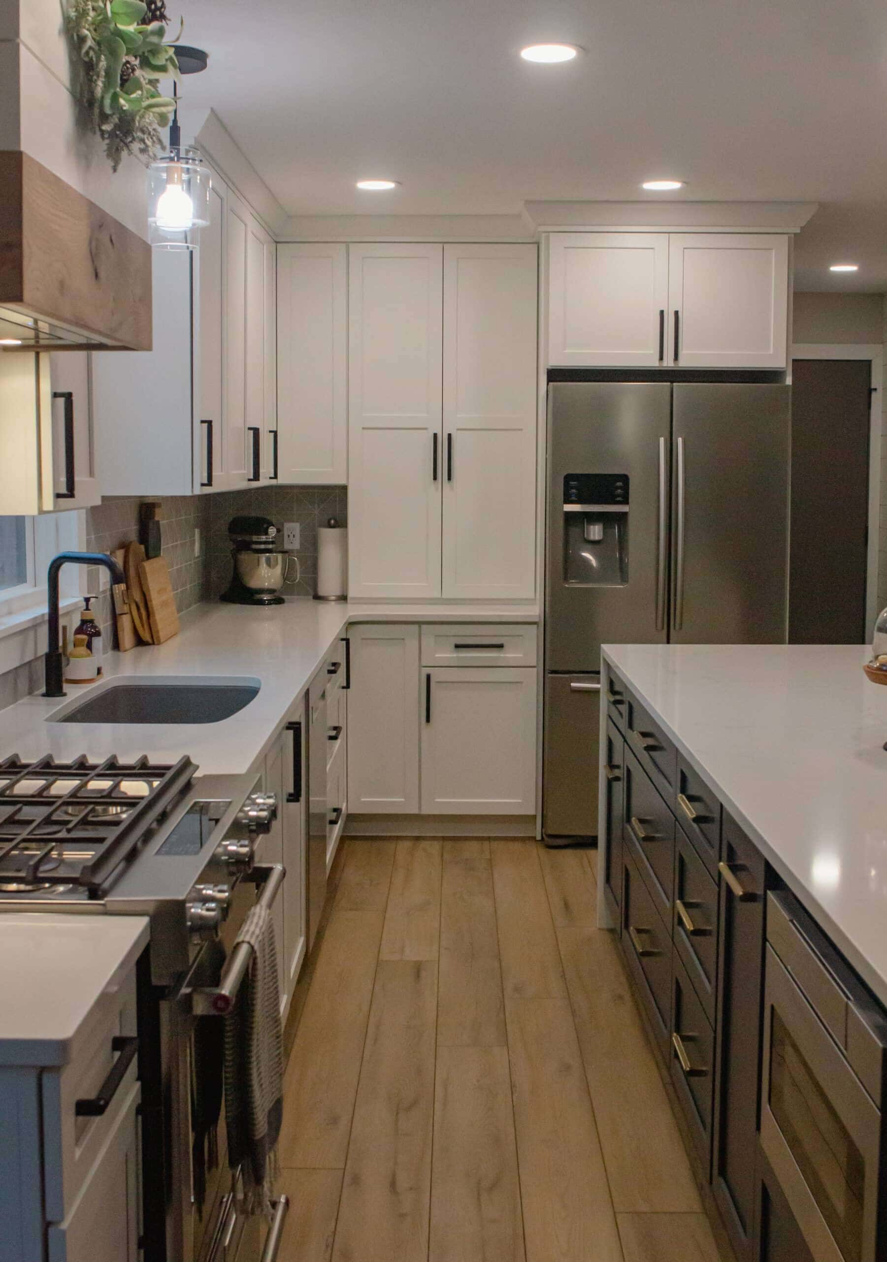Contemporary kitchen with white cabinets, stainless steel appliances, and wooden flooring.
