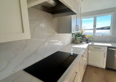 Contemporary kitchen with marble backsplash and black cooktop.