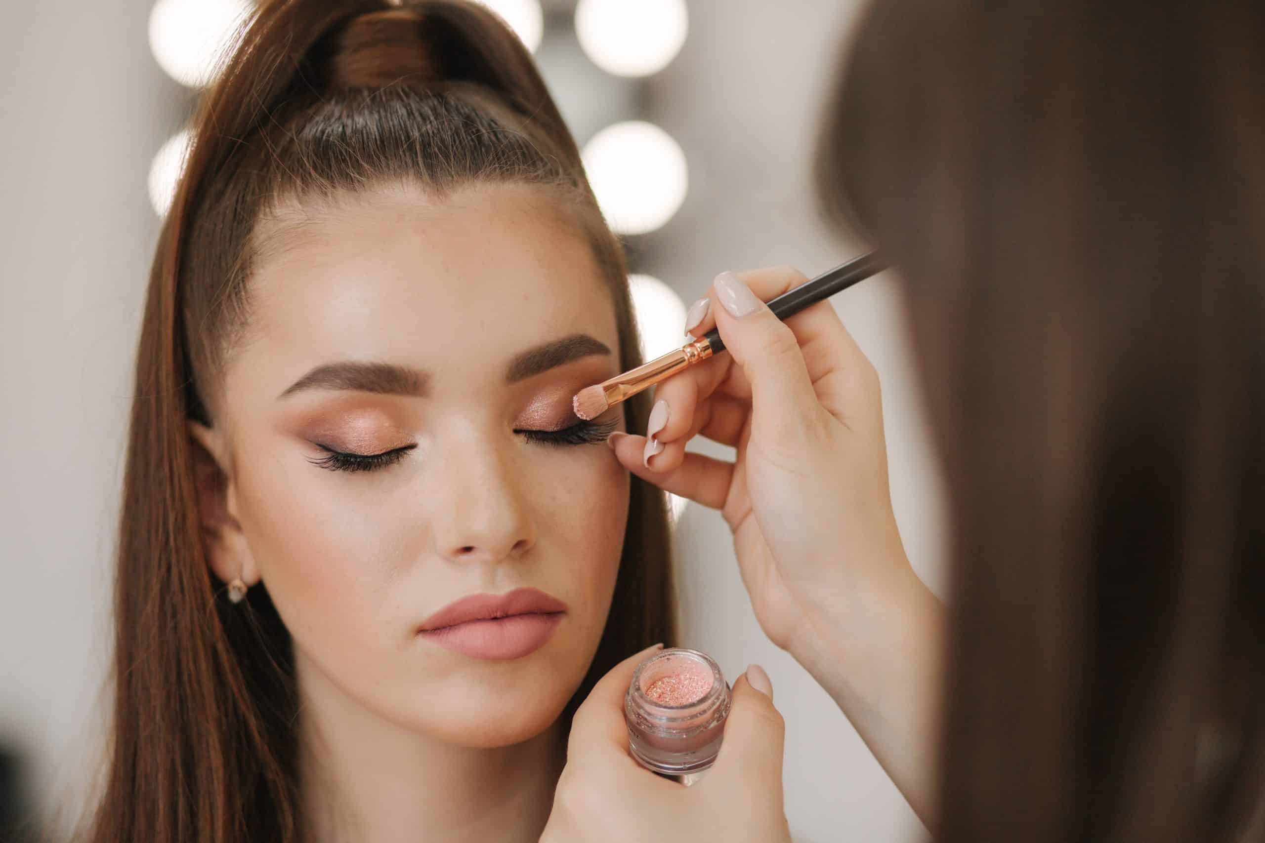 Makeup artist applying eyeshadow to a woman at a beauty spa.