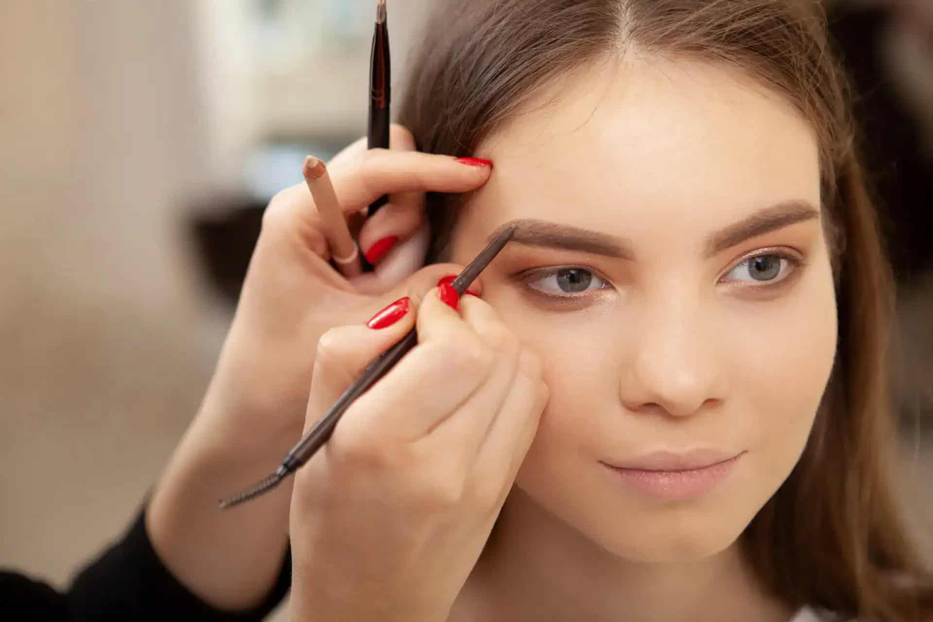 Makeup artist applying eyebrow makeup to a young woman at Beauty Bar & Spa.