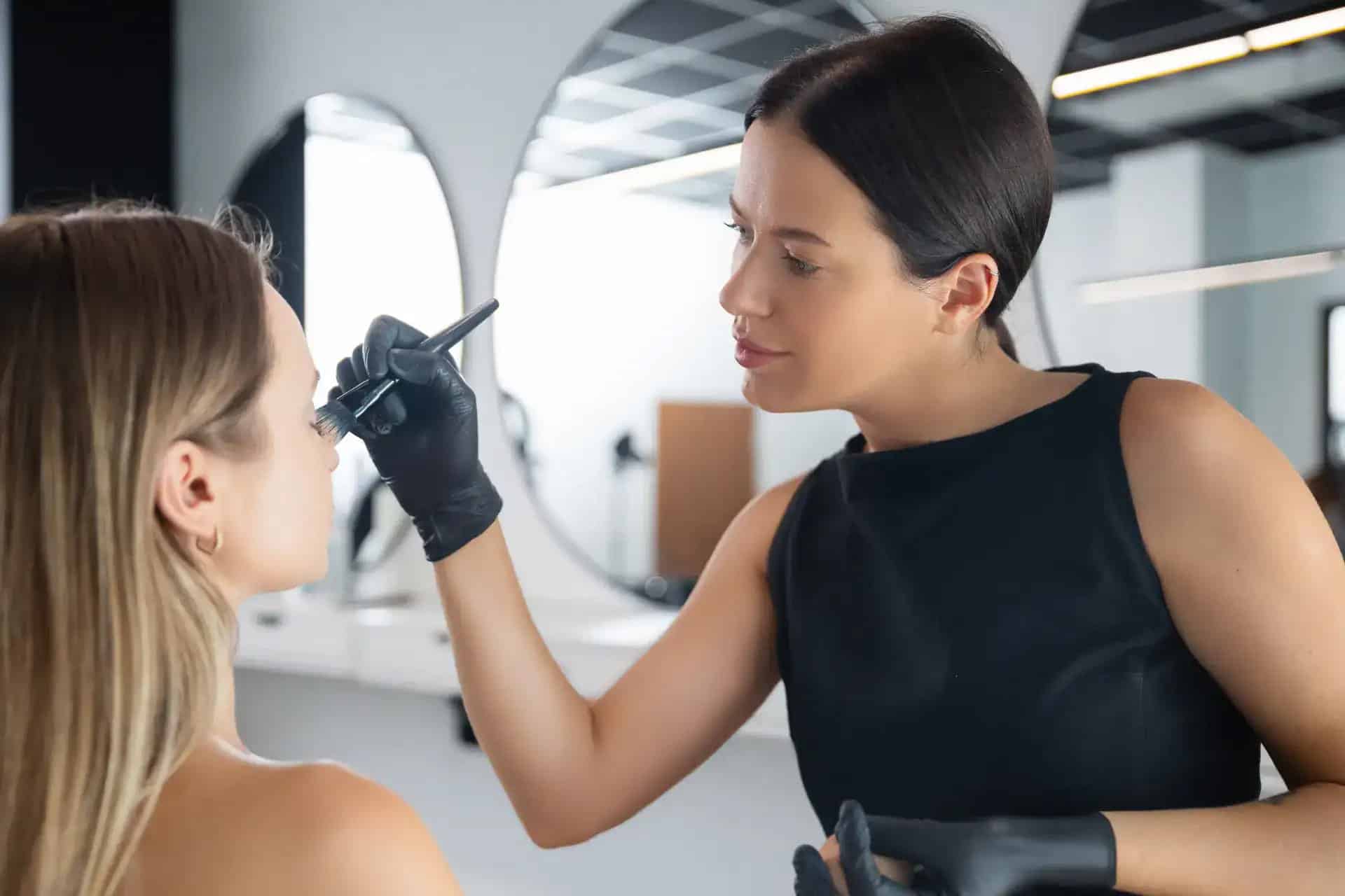 Beauty professional applying makeup to bride in spa setting.