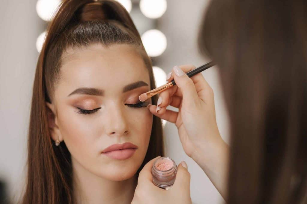 Makeup artist applying eyeshadow to woman at beauty spa.