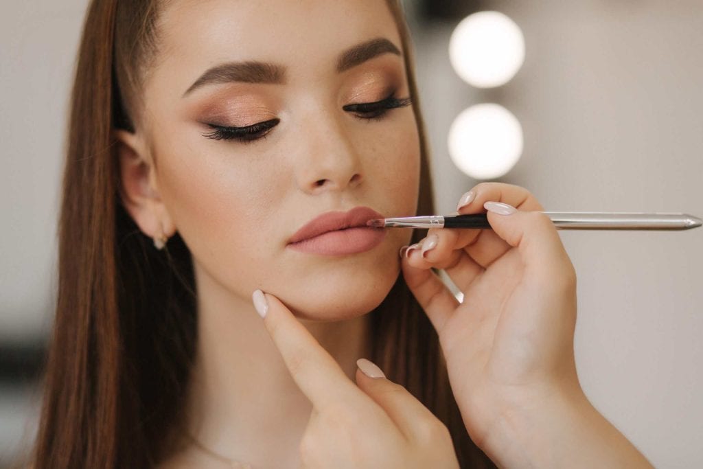 Makeup artist applying lipstick at Beauty Bar & Spa.