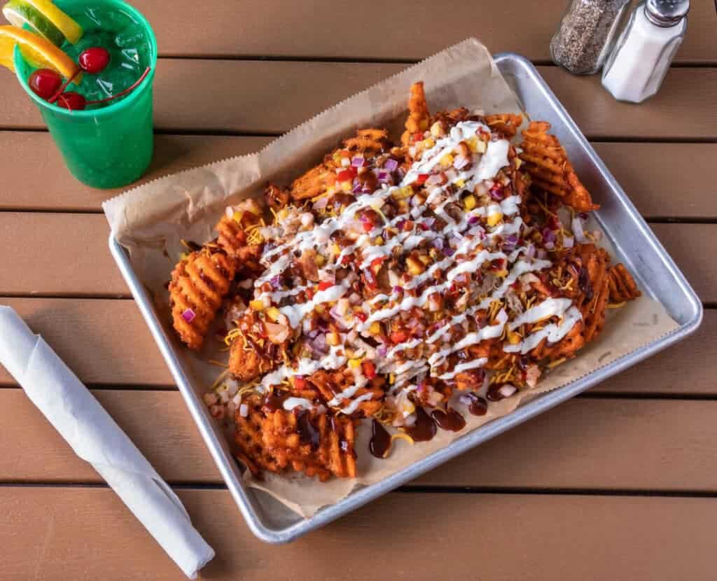 Loaded nachos with cheese, sour cream, and toppings on a tray.