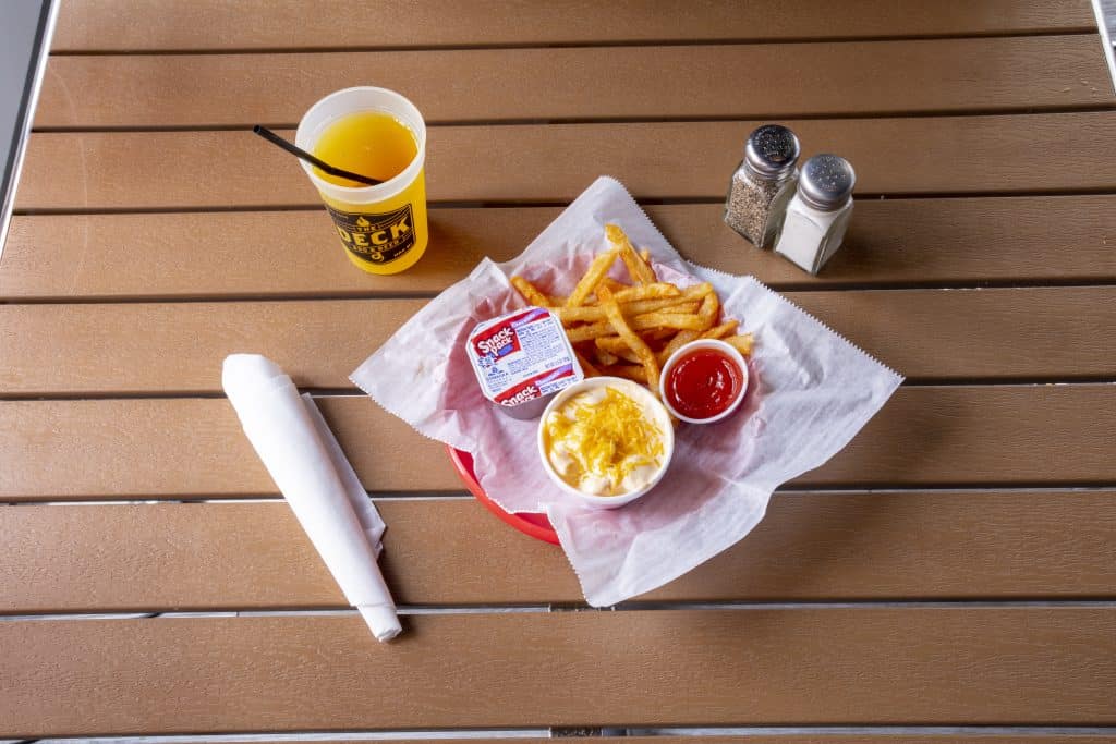 Plate of fries, cheese, ketchup, and drinks on a wooden table.
