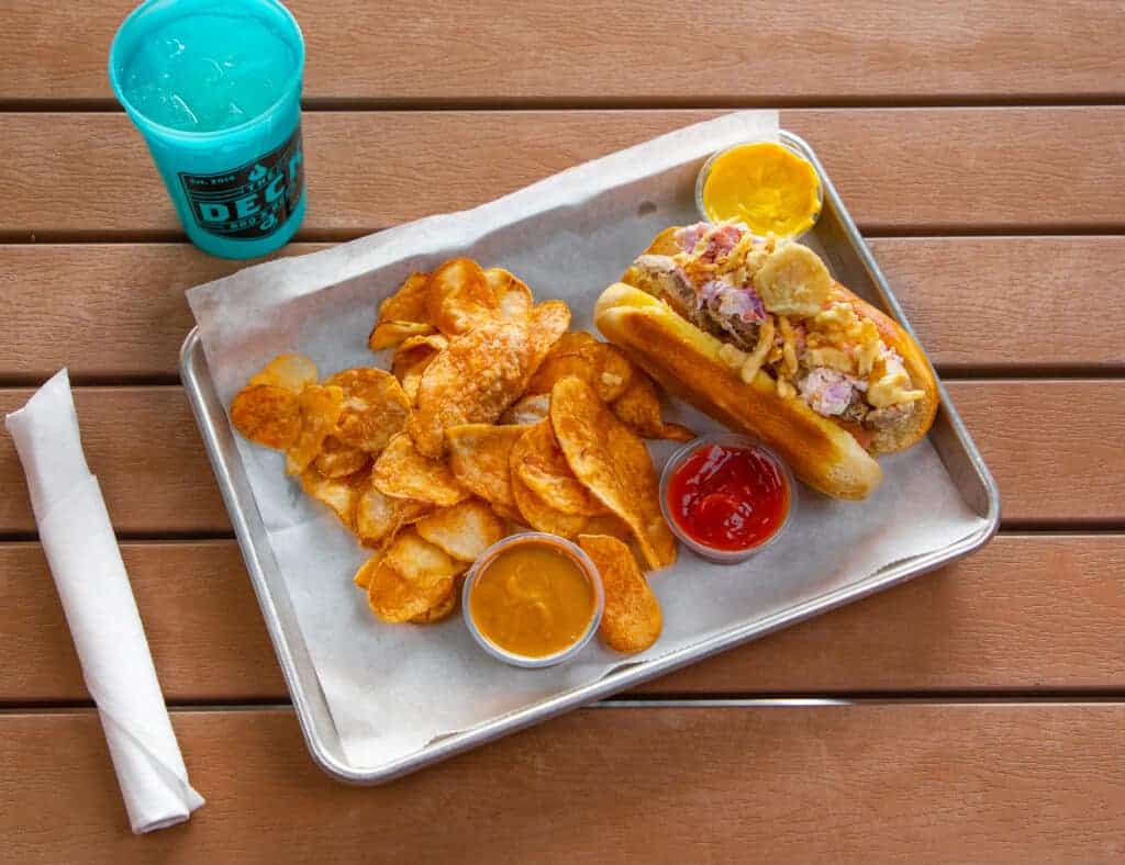 Hot dog with chips and drinks on a metal tray at The Deck.