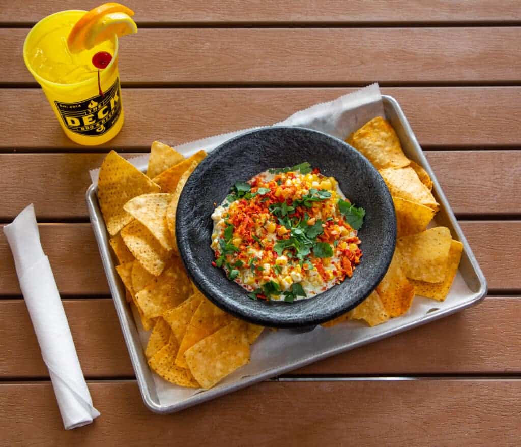 Mexican street corn dip served with tortilla chips on a tray.
