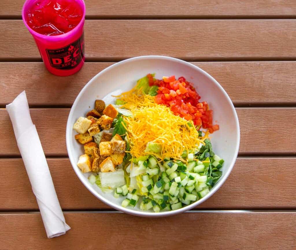 Colorful salad with diced cucumbers, tomatoes, shredded cheese, and croutons.