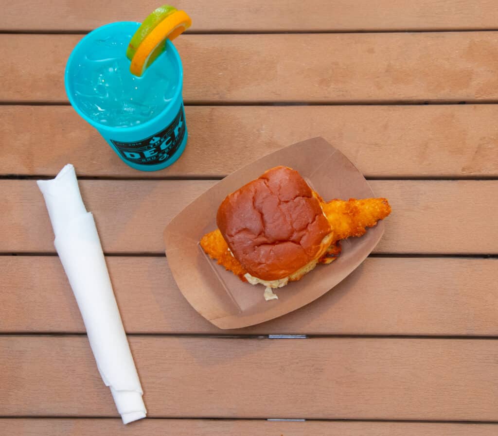 Walleye sandwich with crispy fish fillet and bun on a wooden table.