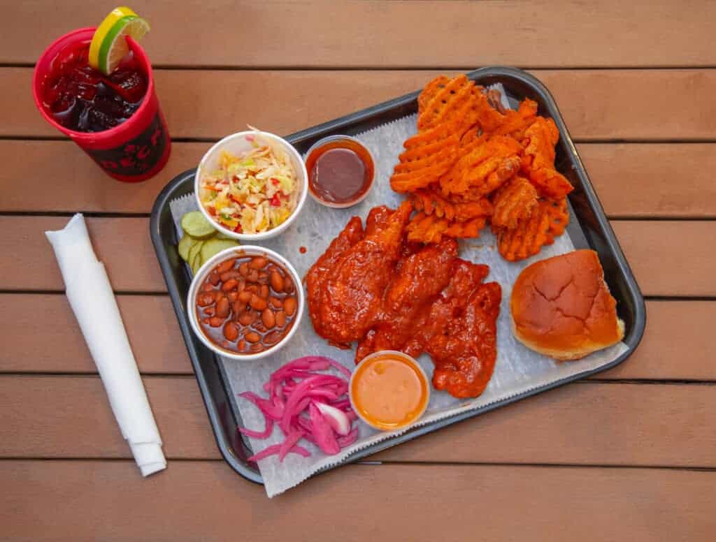 Nashville hot chicken with waffle, waffle fries, coleslaw, baked beans, pickles, and drink.