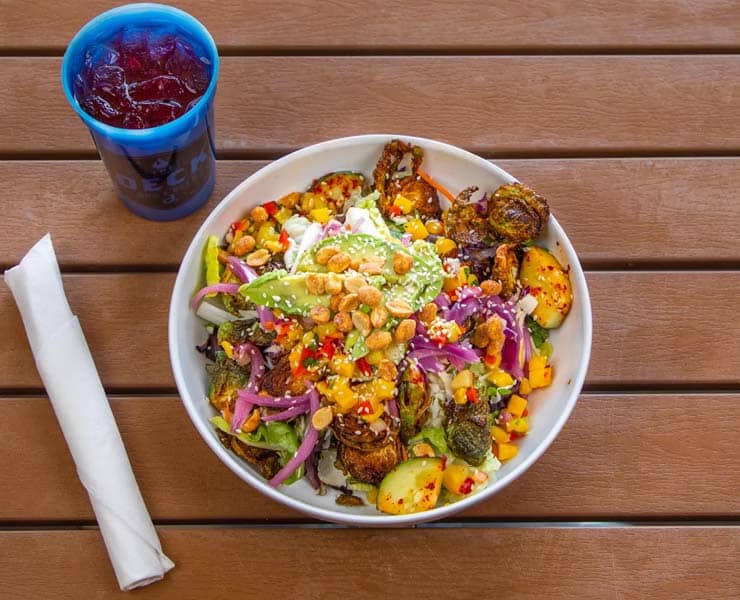 Fresh salad with grilled vegetables, nuts, and colorful toppings on a wooden table.