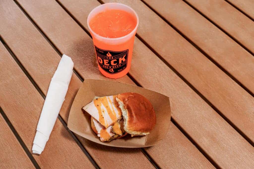 Smoked turkey sandwich with orange drink on wooden table.