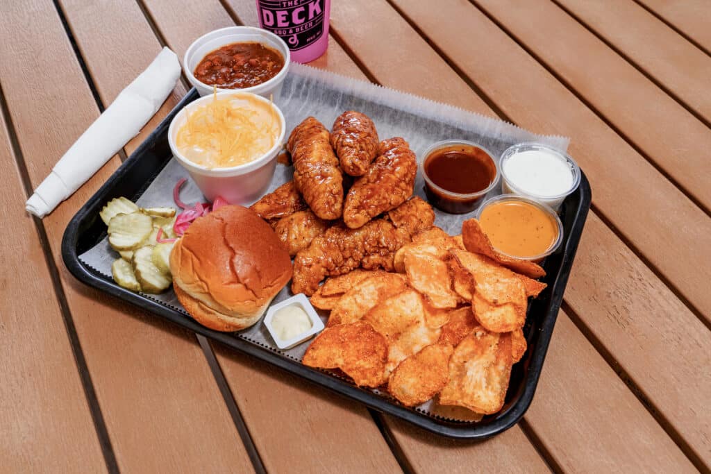 Fried chicken with sauces, biscuit, and pickles on a tray.