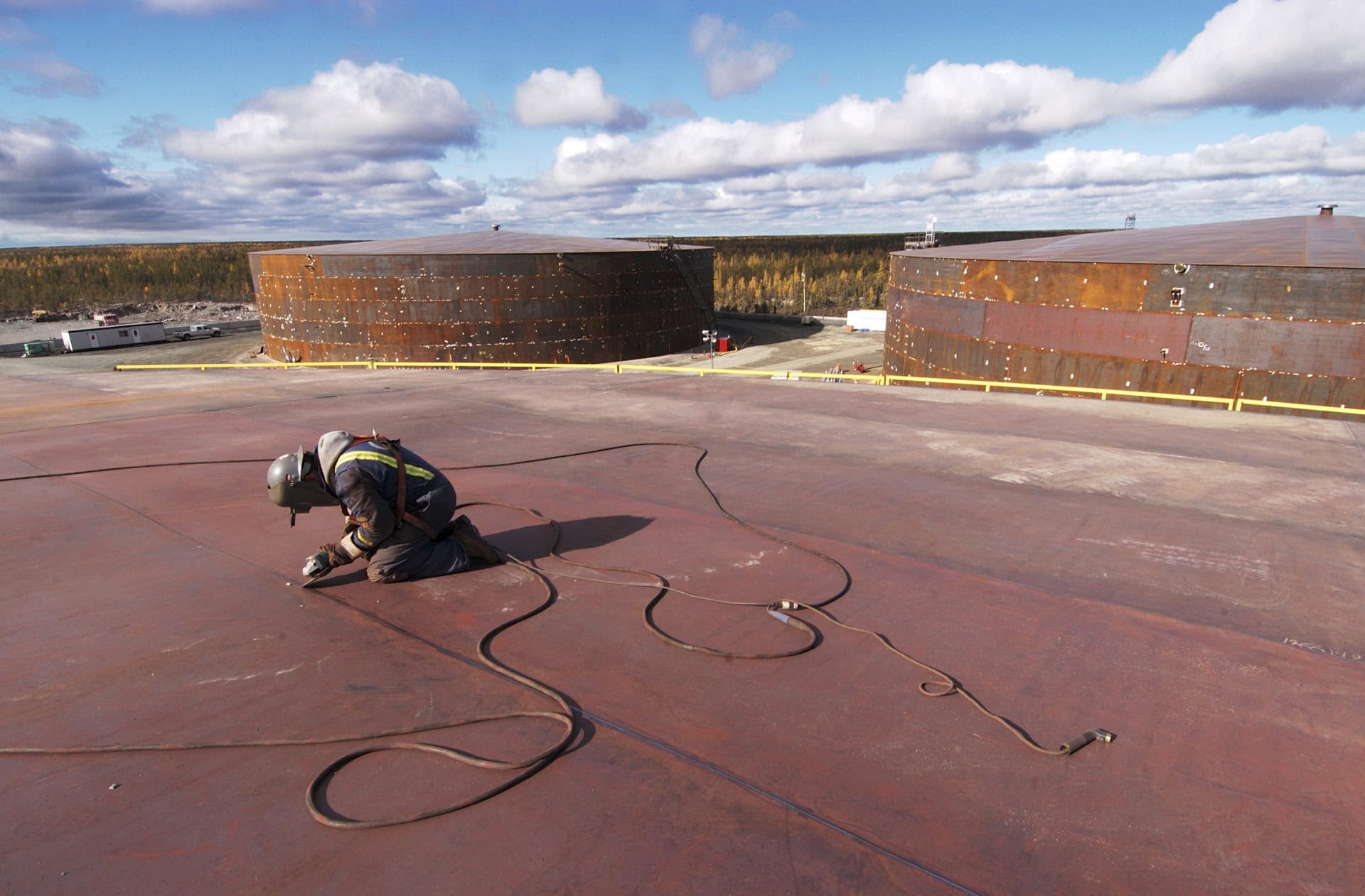 A welder works on the roof a fuel container at a tank farm in Yellowknife, NT.