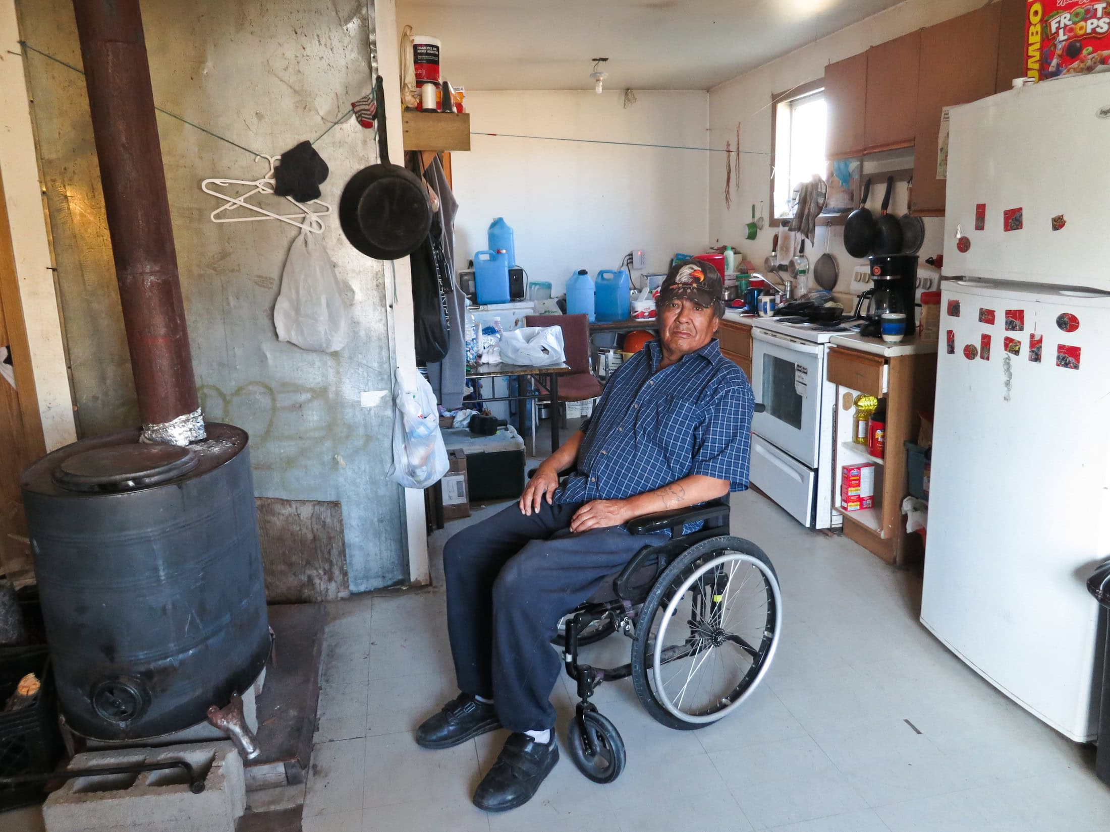 Walter Sakanee, an elder living in Neskantaga First Nation, has had difficulty fighting infections in his legs. He relies on his family members to collect safe drinking water for him in blue plastic jugs from a reverse osmosis machine located at the community’s water treatment plant. He is not able to access the plant on his own due to his physical disability. Photo: Samer Muscati / Human Rights Watch