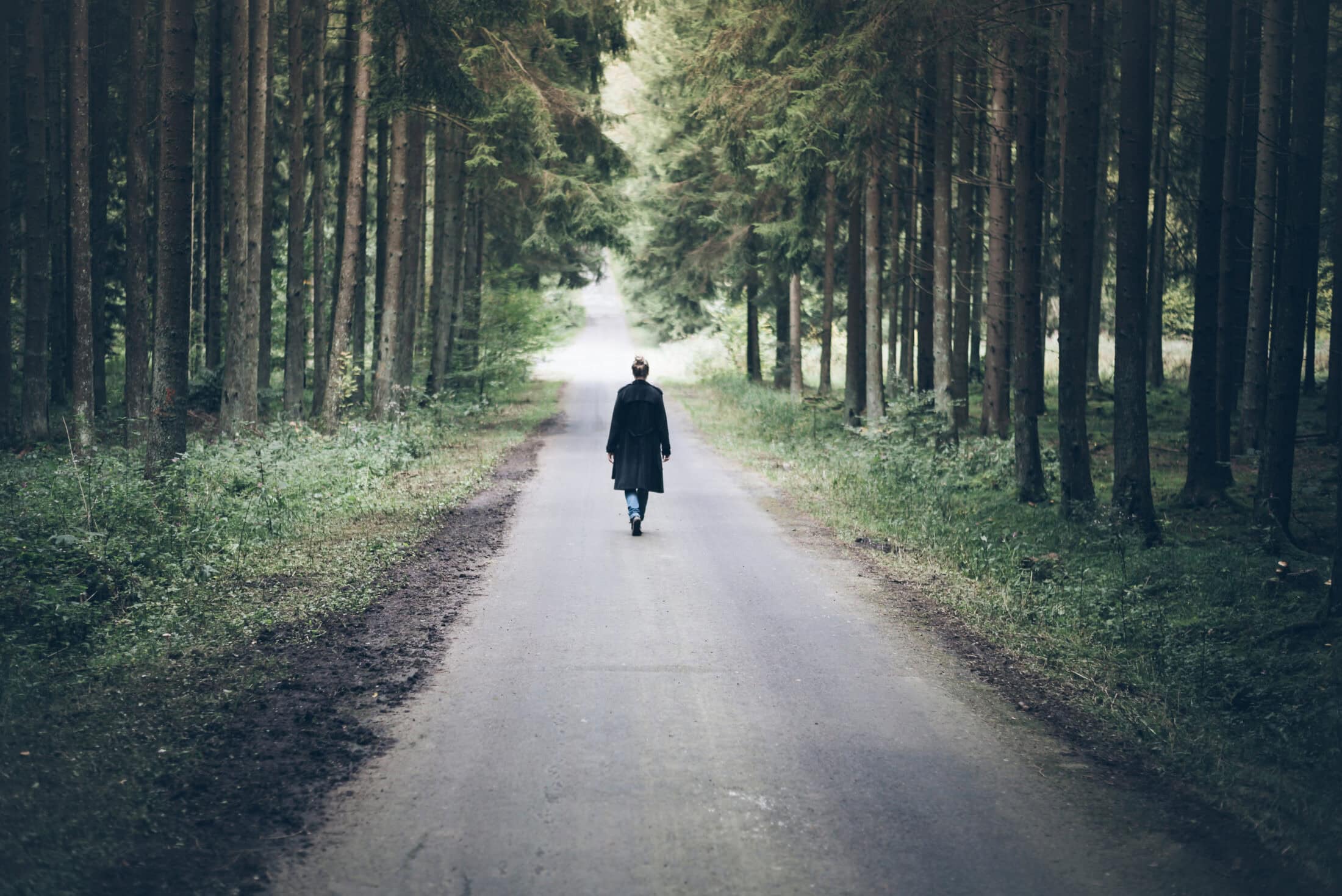 Young,Blonde,Caucasian,Woman,Walking,On,Narrow,Road,Through,Dark